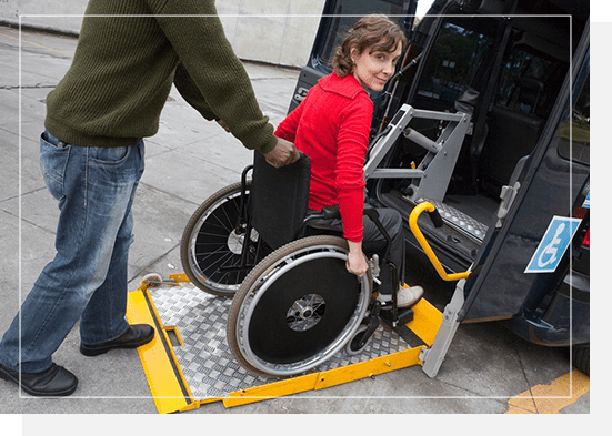 A woman in a wheelchair is getting off of the bus.